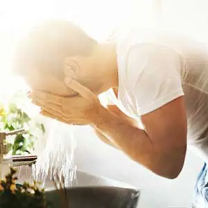 Mann w&auml;scht sich das Gesicht